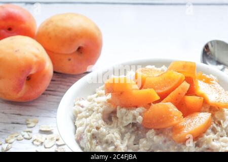 Haferflocken-Haferbrei mit frischen Aprikosen auf Holzgrund. Stockfoto