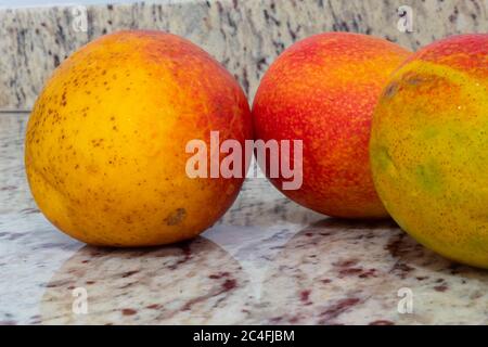 Nahaufnahme von drei bunten Mangos auf hellem Hintergrund Stockfoto