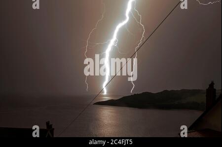 Langland Bay, Swansea, Großbritannien, 25. Juni 2020. Die aktuelle Hitzewelle und das trockene Wetter in ganz Großbritannien enden spektakulär mit einem Gabelblitz am Snapple Point in Langland Bay bei Swansea heute Abend. Stockfoto