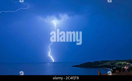 Langland Bay, Swansea, Großbritannien, 25. Juni 2020. Die aktuelle Hitzewelle und das trockene Wetter in ganz Großbritannien enden spektakulär mit einem Gabelblitz am Snapple Point in Langland Bay bei Swansea heute Abend. Stockfoto