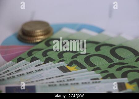 Stapel von Münzen auf 100 Euro-Scheine. Mit Finanzbericht Diagramm Tortendiagramm. Finanzgeschäftskonzept Stockfoto