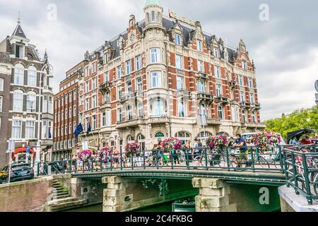 Amsterdam, Niederlande - 18. Juli 2018: Traditionelle holländische Häuser und eine Brücke auf dem Kanal in Amsterdam, Holland. Stockfoto