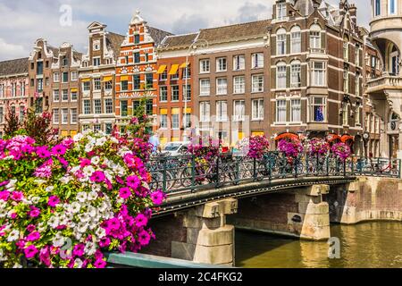 Amsterdam, Niederlande - 18. Juli 2018: Brücke über einen Kanal mit vielen Fahrrädern und Blumen in Amsterdam, Holland. Hochwertige Fotos Stockfoto