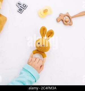 Kinder Hand halten Hase Sitzsack aus natürlichen Materialien auf hellem Marmor Hintergrund. Draufsicht, flach liegend. Stockfoto