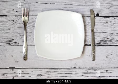 Leere Platte, Gabel und Messer auf Holzhintergrund. Teller und Besteck auf hellem Hintergrund reinigen. Draufsicht. Stockfoto
