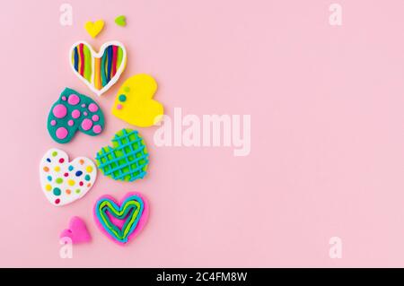 Valentinstag Hintergrund. Bunte handgemachte Herzen aus Plastilin auf rosa Hintergrund mit leerem Platz für Text. Draufsicht, flach liegend. Stockfoto