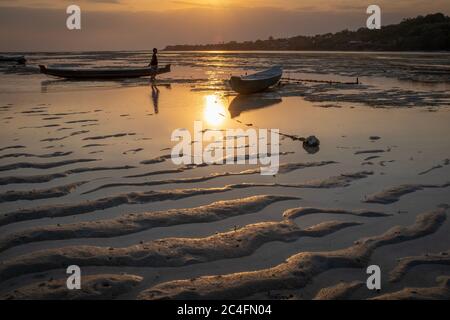 Nusa Ceningan, Bali, Indonesien - 18. Mai 2018: Zwei Boote, die bei Sonnenuntergang auf Sand gestrandet sind, mit einer nicht erkennbaren Person Stockfoto