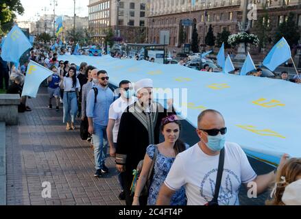 Krimtataren Menschen halten während der Feier Nationalflaggen.Krimtataren feiern jährlich am 26. Juni den Krimtatarischen Flaggentag. Die Flagge der Krimtataren ist ein blaues Tuch mit einem gelben Emblem - Tamga - in der oberen linken Ecke. Die Flagge wurde erstmals 1917 vom Kurultai (Nationalkongress) der Krimtataren nach der Februarrevolution in Russland angenommen. Am 30. Juni 1991 hat der neu einberufene Kurultay diese Flagge als nationale Flagge wieder aufgenommen, so Wikipedia. Stockfoto