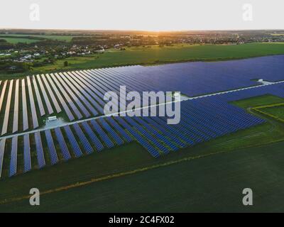 Luftdrohnenaufnahme von großen Solarzellen auf einer Solarfarm bei strahlendem Sommersonnenuntergang. Solarzellen Kraftwerke, bunte Foto Stockfoto