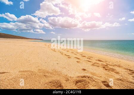 Leerer, menschenleerer goldener Strand mit Muschelsand und kristallklarem azurblauem Meer. Verschwommener Hintergrund für Ihren Text. Reisekonzept, idealer Ort für den Sommer Stockfoto