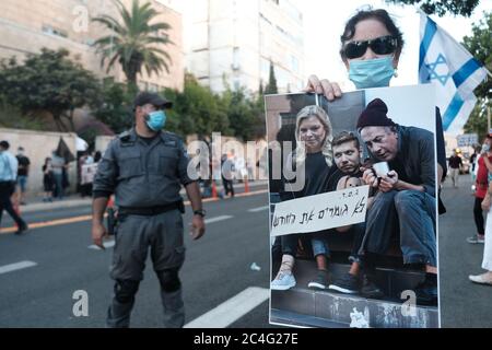 Jerusalem, ISRAEL 26. Juni 2020: Ein Demonstranten hält ein Plakat, das den israelischen Ministerpräsidenten Benjamin Netanjahu und seine Familie verspottet, während Hunderte von Unterstützern der sogenannten Anti-Korruptionsbewegung der Schwarzen Flagge vor der offiziellen Residenz von Premierminister Benjamin Netanjahu demonstrierten und ihn angesichts der Korruptionsvorfälle gegen ihn in Jerusalem, Israel, zum Rücktritt forderten. Quelle: Eddie Gerald/Alamy Live News Stockfoto