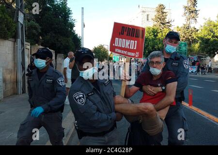 Jerusalem, ISRAEL 26. Juni 2020: Ein Demonstranten, der ein Plakat mit der Aufschrift "mit korrupten aufgezettelt" hält, wird von Polizeibeamten weggeschleppt, während Hunderte von Anhängern der Anti-Korruptionsbewegung der Schwarzen Flagge vor dem Haus von Premierminister Benjamin Netanjahu demonstrierten und ihn angesichts der Korruptionsvorwürfen gegen ihn in Jerusalem, Israel, zum Rücktritt forderten. Quelle: Eddie Gerald/Alamy Live News Stockfoto