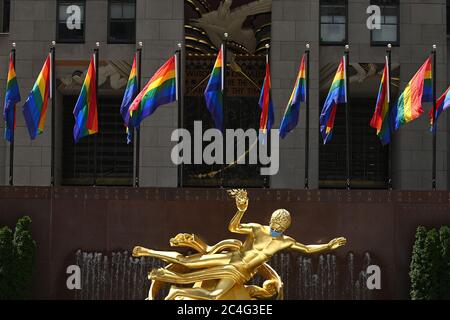 New York City, USA. Juni 2020. Regenbogenfahnen fliegen über Prometheus (geschmückt mit einer blauen Gesichtsmaske, um die soziale Distanzierung in der Zeit von COVID-19 zu fördern), werden um die Rink am Rockefeller Center zur Feier des Pride in New York, NY, 26. Juni 2020 aufgestellt. (Anthony Behar/Sipa USA) Quelle: SIPA USA/Alamy Live News Stockfoto