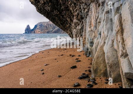 Blick auf das Sonnenuntergangsmeer und den Strand, das vulkanische Gestein, Sand und Kieselsteine, vulkanischen Basalt wie in Island. Speicherplatz kopieren. Das Konzept der Ruhe, Stille Stockfoto