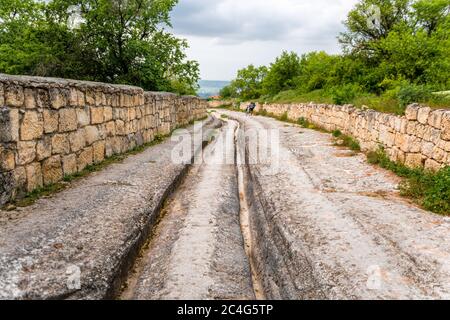 Eine Höhlenstadt in den Bergen, eine alte Steinstraße mit gebrochenen Furchen von den Rädern. Stockfoto