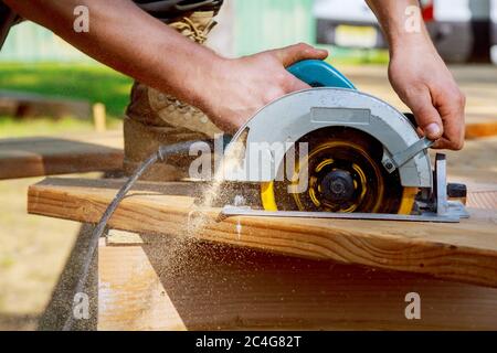 Builder sägen ein Board mit einer Kreissäge im Schnitt einer Holzbohle Stockfoto