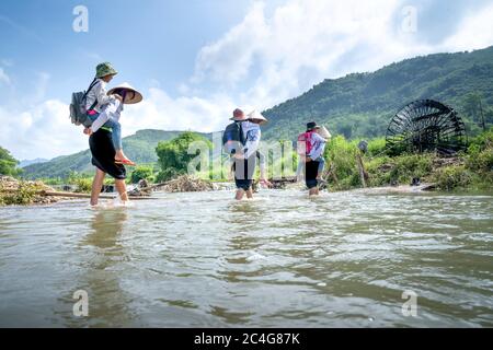 Provinz Phu Tho, Vietnam - 28. Mai 2020: Frauen ethnischer Minderheiten tragen ihre Kinder durch den großen Strom, um zur Schule zu gehen Stockfoto