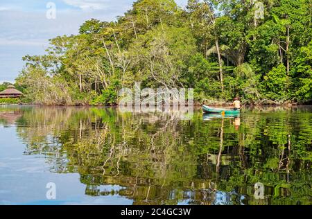 Indigener Kichwa-Mann paddelt mit dem Kanu zu einer Amazonas-Regenwald-Lodge in Ecuador. Stockfoto