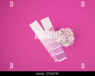 Ein Blumenstrauß aus Frühlingsblumen in einer Gießkanne und eine Blumenpalette auf einem rosa Hintergrund. Stockfoto