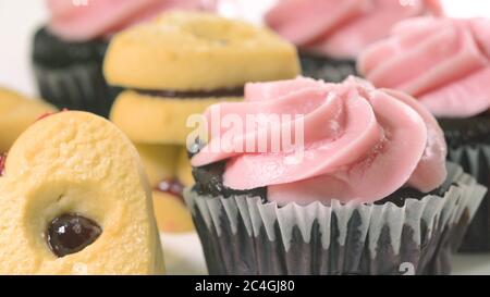 Schokoladenkuchen mit Himbeer-Buttercreme-Aufschäumen und herzförmigen Plätzchen schließen sich auf weißem Hintergrund, Draufsicht. Stockfoto