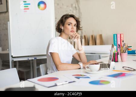 Junge schöne Dame mit kurzen lockigen Haaren in kabellosen Kopfhörern Stockfoto