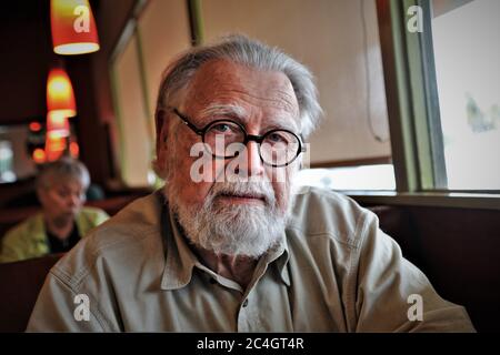 Älterer älterer Mann mit Brille ein Bart und fragende Blick auf den Fotografen im vollen Gesicht und grauen Haaren Stockfoto