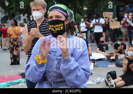 New York, New York, USA. Juni 2020. Nach wochenlangen Protesten gegen Polizeibrutalität und rassistische Ungerechtigkeit zelten die Demonstranten in New York City vor dem Rathaus, um eine Milliarde Dollar an Kürzungen der NYPD-Finanzierung vor dem 1. Juli der Stadt zu fordern. Diese maskierte Gesichtsfrau applaudiert den Müttern, die die Geschichte des Todes ihres Sohnes erzählen, der von der NYPD erschossen wurde. Befürworter der Polizeireform sagen, dass das fast 6 Milliarden Dollar schwere Polizeibudget der Stadt deutlich gekürzt und in Wohnungen, Gesundheitsversorgung und andere soziale Dienste reinvestiert werden muss. Quelle: Marie Le BLE/ZUMA Wire/Alamy Live News Stockfoto