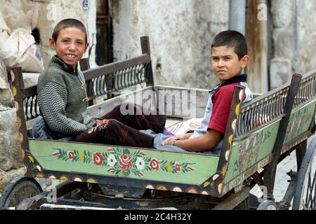 Türkische Jungen sitzen in einem Holzwagen auf einer Straße in der Stadt Goreme in der Region Kappadokien in der Türkei. Stockfoto