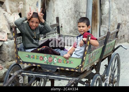 Türkische Jungen sitzen in einem Holzwagen auf einer Straße in der Stadt Goreme in der Region Kappadokien in der Türkei. Stockfoto