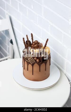 Elegante Schokolade Geburtstagskuchen mit geschmolzener dunkler Schokolade, Cupcake, Cake Pops, Kekse und Süßigkeiten auf weißem Hintergrund. Stockfoto