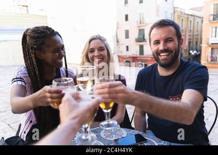 Freunde trinken auf der Terrasse einer Bar. Die Kamera toastet mit seinen Freunden glücklich. Neues Normalitätskonzept Stockfoto