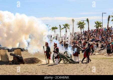 Malaga, Spanien - 26. Oktober 2014: französische Soldaten aus dem 18. Jahrhundert feuern eine Kanone. Rauch von Schießpulver. Reenactors mit einer Menge hinter ihnen. Historische RE Stockfoto