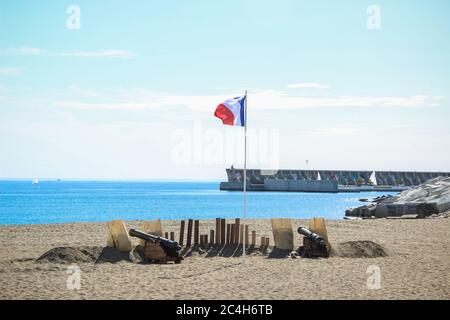 Malaga, Spanien - 26. Oktober 2014: Französische Flagge fliegt zwischen zwei Kanonen an einem Strand neben dem Hafen. Historische Nachstellung einer napoleonischen korsaren Stockfoto