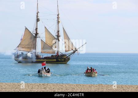 Malaga, Spanien - 26. Oktober 2014: Brig La Grace feuert seine Kanonen, Soldaten rudern in zwei Booten. Historische Nachstellung der britischen Landung von 1812. Stockfoto