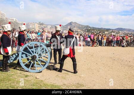 Malaga, Spanien - 26. Oktober 2014: französische Soldaten des 18. Jahrhunderts laden eine Kanone mit Schießpulver. Männer und Frauen reenactors. Die Menge wartet herum. Hist Stockfoto