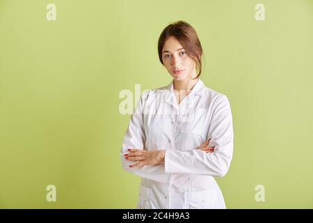 Praktikant Doktor Junge hübsche Frau in weißen Kleidern posiert auf einem grünen Hintergrund. Speicherplatz kopieren. Stockfoto