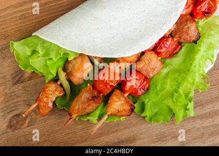 Gebackenes Schweinefleisch auf Spieße mit Tomaten und Paprika in Pita Brot und Salat auf dem Brett Stockfoto