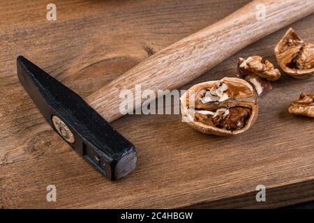 Walnuss und Hammer auf einem Holzbrett Stockfoto