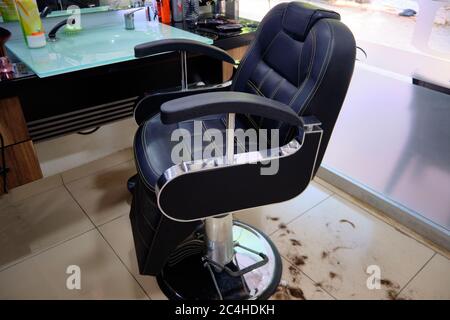 Friseurstuhl und Haare auf dem Boden in einem Schönheitssalon. Stockfoto