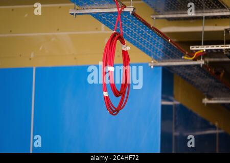 Die Spule des Elektrokabels hängt von der Decke im Gebäude im Bau Stockfoto