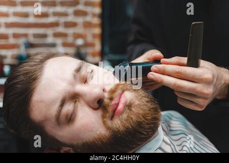 Master Friseur schneidet Client-Bart mit elektrischen Trimmer Stockfoto