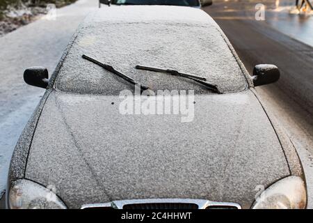 Vorderansicht der Scheibenwischer und der mit Eis und Schnee bedeckten Milchautoscheibe. Stockfoto