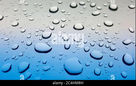 Spritzer von Regentropfen auf einer Autoscheibe nach einem Sturm. Abgewinkelter Blickwinkel für Schärfentiefe und selektiven Fokus. Stockfoto