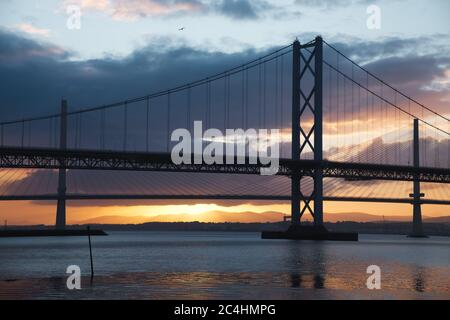 Zwei Brücken gegen die untergehende Sonne und das Meer, Forth Road Brtidge und Queensferry Crossing, Schottland, Vereinigtes Königreich Stockfoto