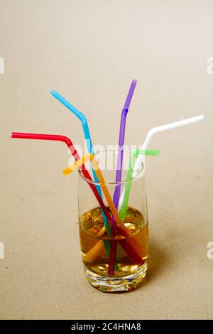 Bunte Röhren in einem Glas mit einem gelben Getränk - Seitenansicht Stockfoto
