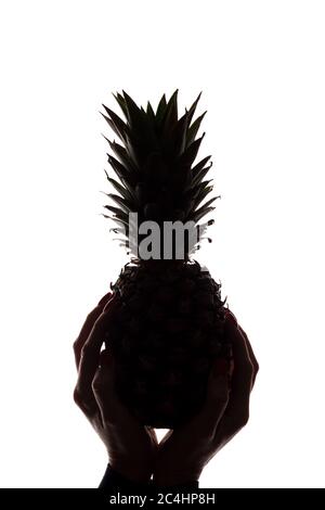 Ananas auf den Händen einer Frau auf weißem Hintergrund - vertikale Silhouette Stockfoto