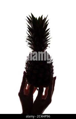 Ananas auf den Händen einer Frau auf weißem Hintergrund - vertikale Silhouette Stockfoto