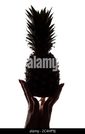 Ananas auf den Händen einer Frau auf weißem Hintergrund - vertikale Silhouette Stockfoto