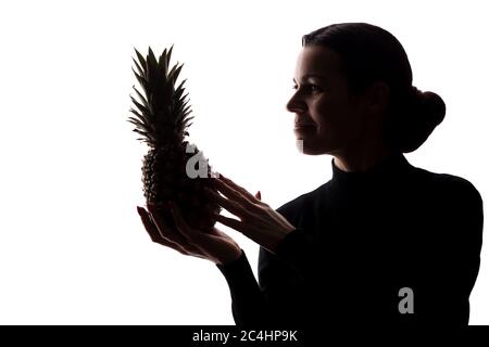 Ananas auf den Händen einer Frau auf weißem Hintergrund - Silhouette Stockfoto