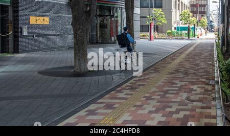 Polizist, der auf dem Bürgersteig der Shinjuku Straße, Tokio, Japan, Fahrrad fährt Stockfoto